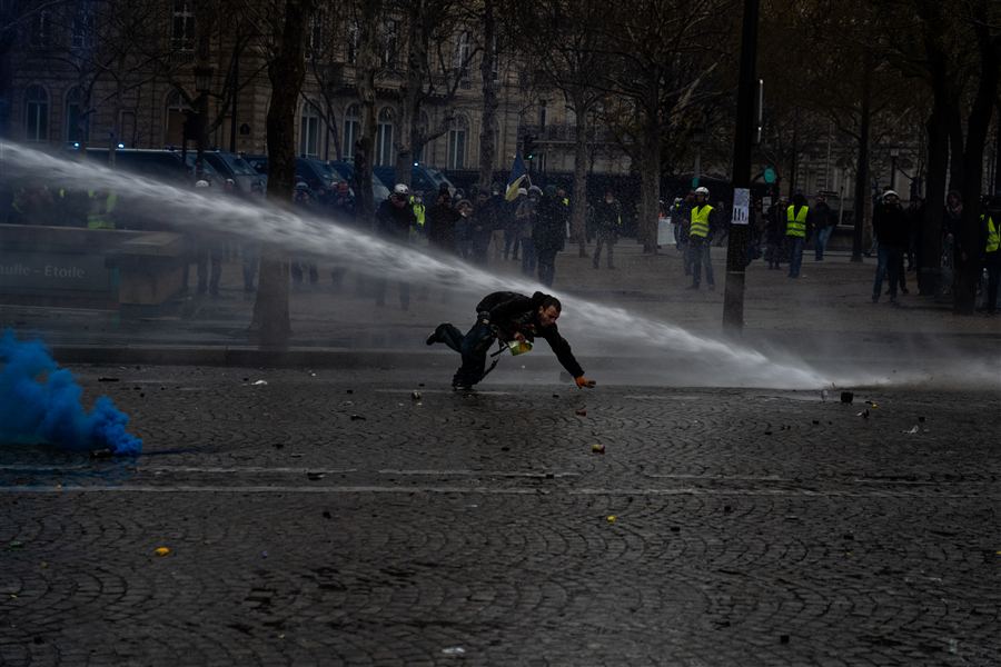 Manifestant courant dans la fumée et les jets d'eau
