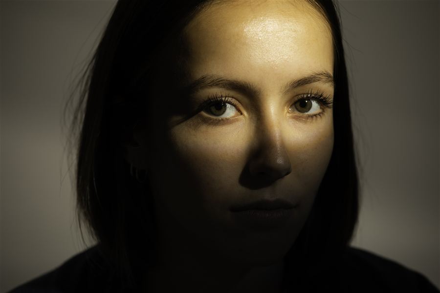Portrait rapproché d'une femme, regard éclairé dans la pénombre
