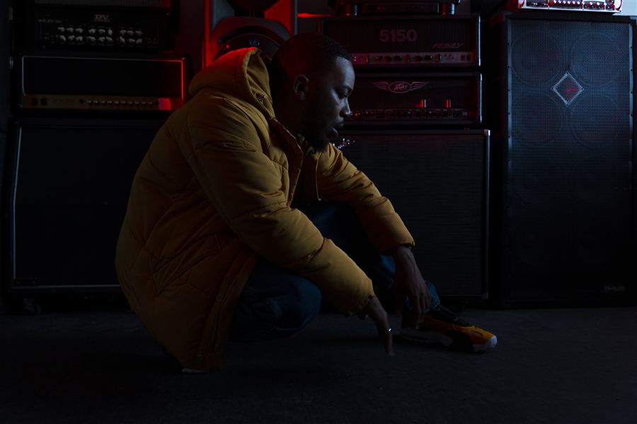 Homme en veste jaune assis devant un fond sombre