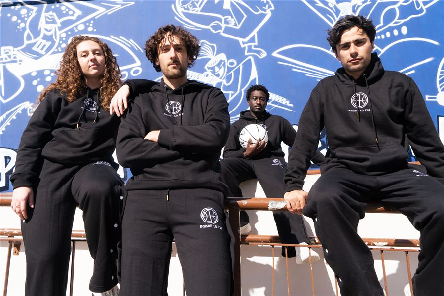 Collectif en vêtements noirs devant une fresque bleue