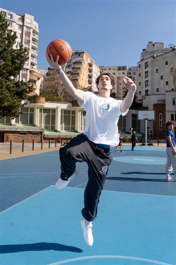 Joueur en tenue de basket sur un terrain extérieur bleu