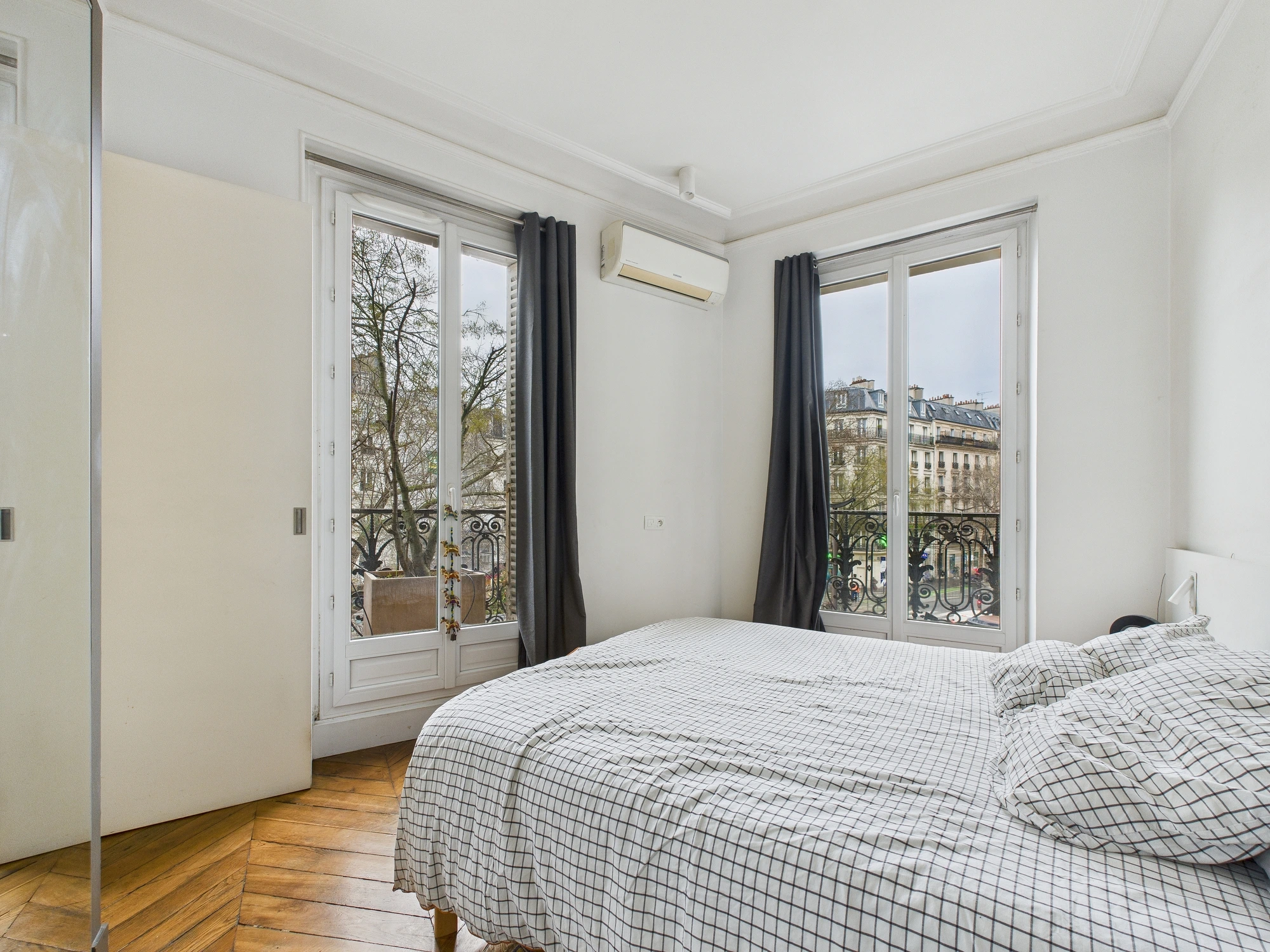 Chambre avec grandes fenêtres donnant sur les façades parisiennes